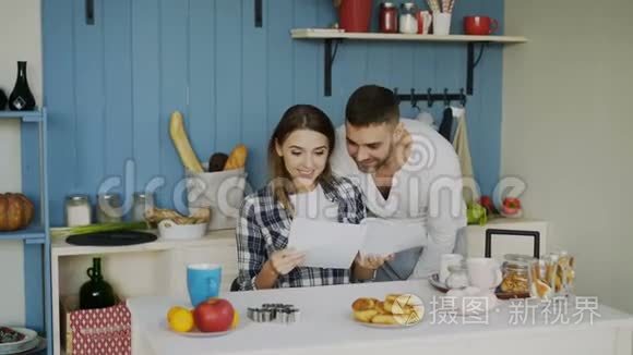 一对漂亮的幸福夫妇在家吃早餐时，在厨房里收到一封正在展开的好消息