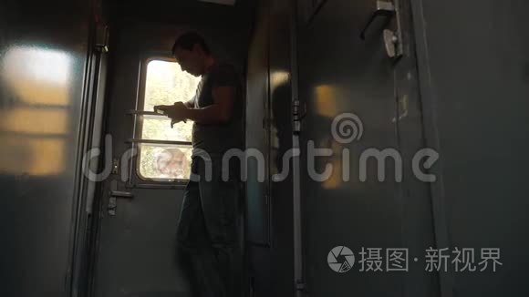 那个人的轮廓站在火车车厢上，手里拿着一部智能手机。 慢动作视频。 男人写字