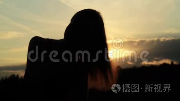 一个女人在夕阳下梳头的剪影视频