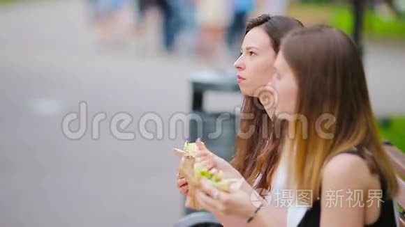 高加索女人在户外的街上吃汉堡包快餐三明治。 饥饿的活跃女孩和吃街头食品的女孩