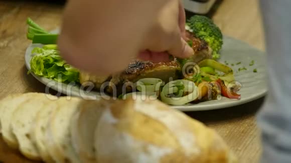 女人把肉排和蔬菜放在盘子里视频的预览图