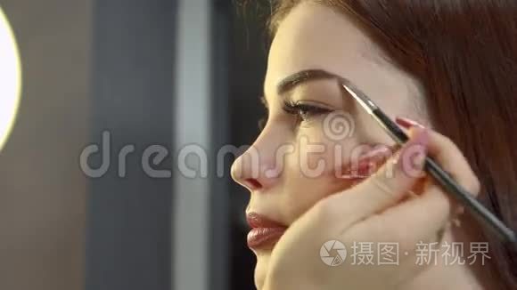一个深色头发的女孩在美容院接受化妆。