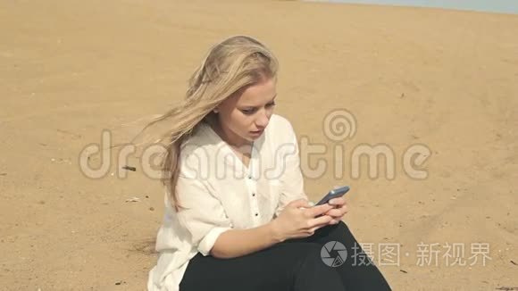 美丽的女孩坐在沙滩上打电话
