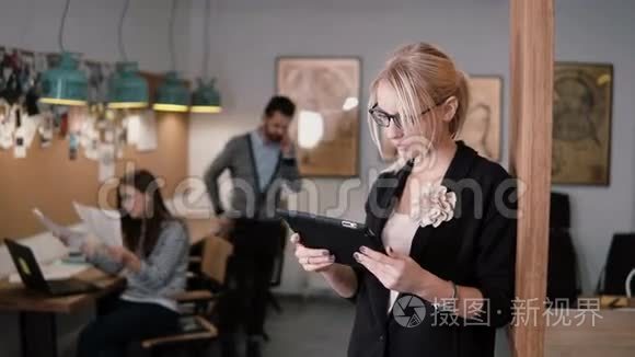 4k. 特写年轻漂亮的金发女商人在现代创业办公室使用触摸屏平板电脑。