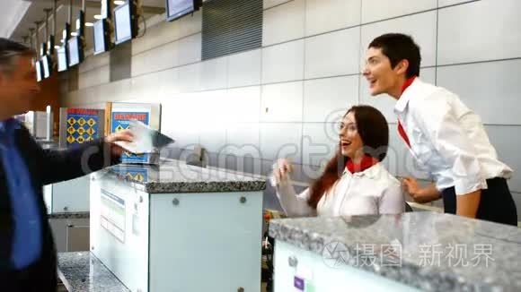 两名女机场工作人员在登记台检查护照并与男子互动