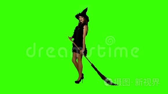 万圣节女巫在绿色屏幕上拿着扫帚