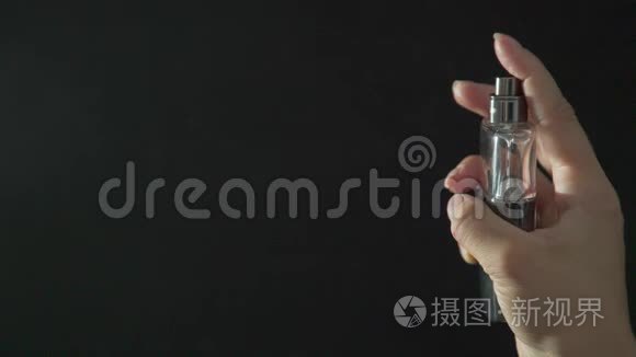 女性手拿着一瓶香水，喷它去感受芬芳。