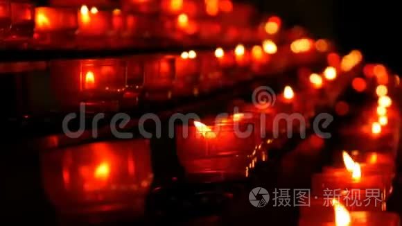 一排基督教祈祷红色的圆形蜡烛在黑暗中燃烧。 祈祷照明祭祀蜡烛近景