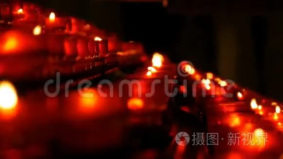 一排基督教祈祷红色的圆形蜡烛在黑暗中燃烧。 祈祷照明祭祀蜡烛近景