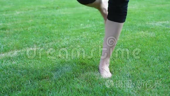 美丽的年轻女子光着脚在夏日草地上的草地上
