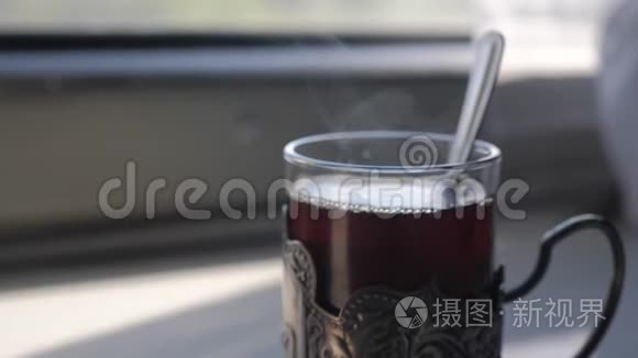 铁路旅行概念。 在玻璃生活方式中用勺子喝茶，老式的，老式的，站在火车车厢的桌子上