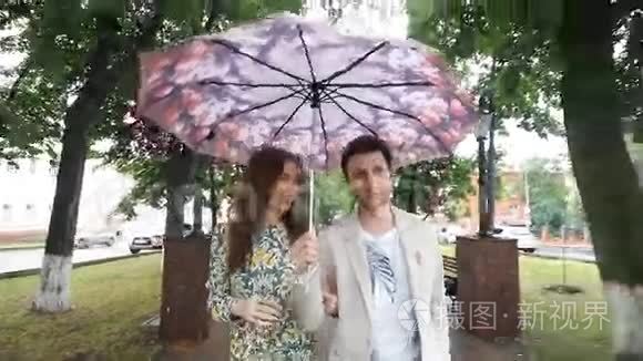 一对漂亮的夫妇在公园的伞下散步
