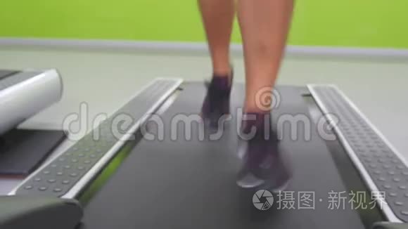 女性腿在健身房的跑步机上慢跑和跑步。 年轻女性在有氧运动中锻炼。 女孩的脚