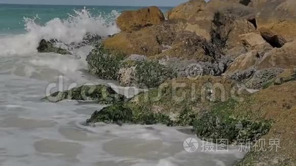 海边是沙质的海岸，岩石上有浪花飞溅.