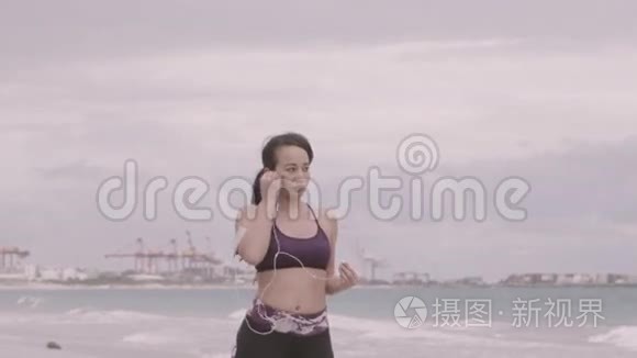 在阴天准备在海滩上慢跑的年轻女子。 健身。 慢动作