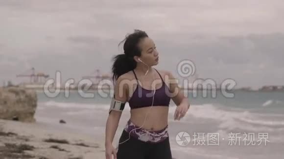 在阴天准备在海滩上慢跑的年轻女子。 健身。 慢动作