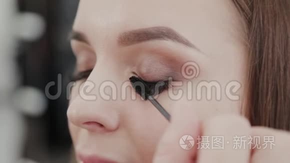 专业化妆师女士为美容院的客户画睫毛。