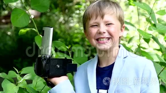 小男孩带着摄像机拍摄大自然中的绿色公园慢动作。