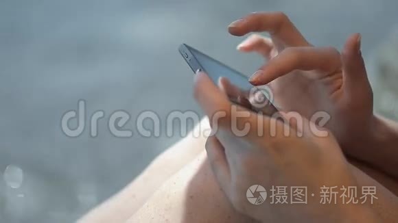 沙滩上使用智能手机的女士双手