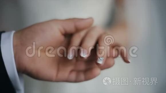 新郎把结婚戒指戴在新娘的手指上。 带戒指的婚姻之手。 新郎新娘交换婚礼