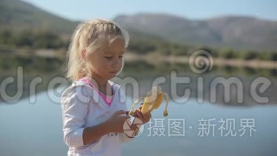 可爱的小女孩站着吃香蕉
