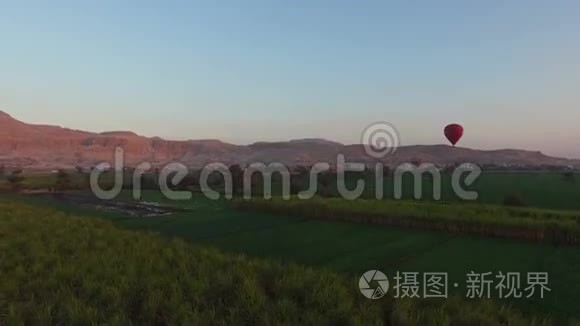日出时，热气球飞过卢克索的田野