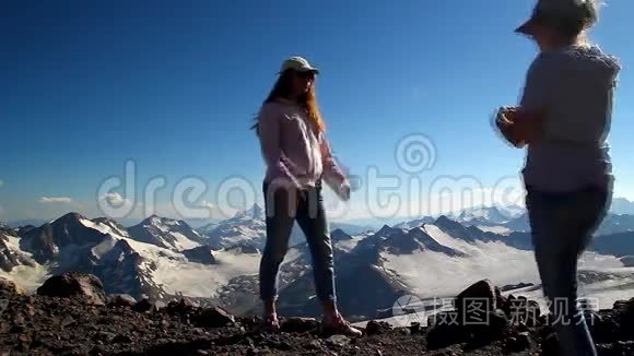 两个快乐的女孩用双臂拥抱在山顶