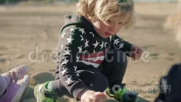 这个男孩正在海滩上玩一辆绿色的玩具自卸卡车。