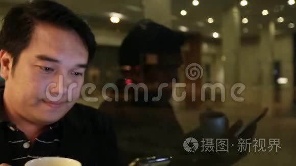 亚洲商人在咖啡馆晚上使用手机和智能手机。 帅哥在等人