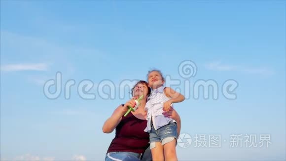 快乐的奶奶带着孩子玩着放风筝，一家人在热带海洋的沙滩上玩耍