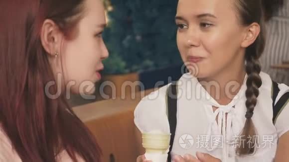 两个年轻的女人吃冰淇淋，坐在户外咖啡馆里，她们玩得很开心。 4K，慢动作，稳定。