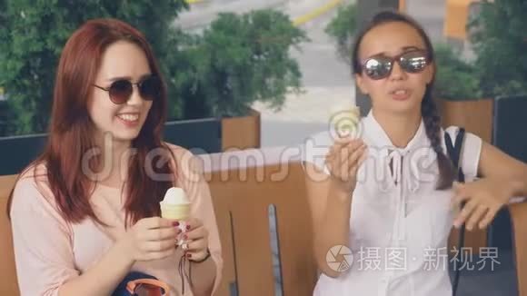 两个年轻的女人吃冰淇淋，坐在户外咖啡馆里，她们玩得很开心。 4K，慢动作，稳定。