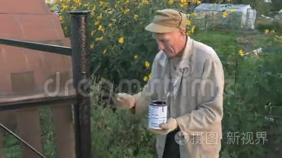 园丁用黑色油漆粉刷铁栅栏视频