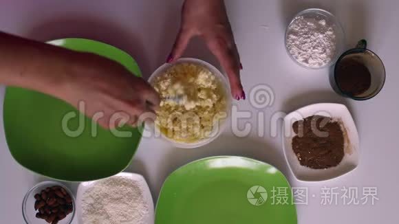 女人用炼乳、椰子刨花和杏仁准备糖果。