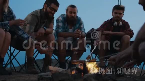 朋友在黄昏的篝火上煎香肠视频