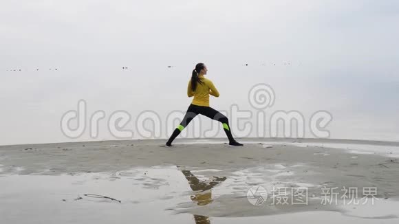 年轻苗条的女人在日落时在海边做健身瑜伽运动。 天与水的无缝自然背景