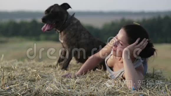 在马槽里养狗的年轻女人。 一个女孩和一只猎犬在田野里的肖像。