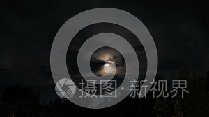 夜月升起在地平线上的树木和云。 时间流逝