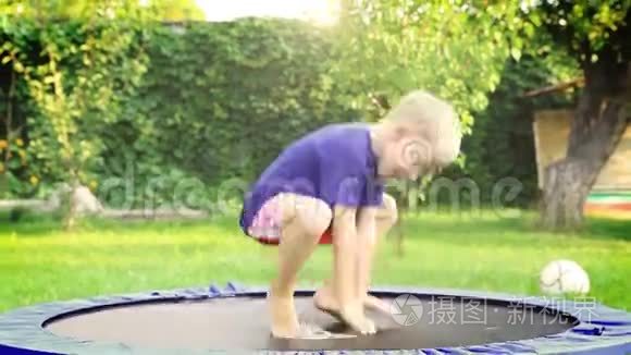 快乐的金发男孩在夏日花园的蹦床上跳