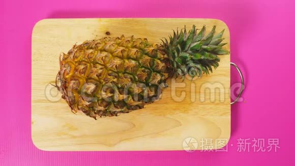 俯视图，女手用刀切水果在木板上，菠萝.. 天然健康食品的概念..