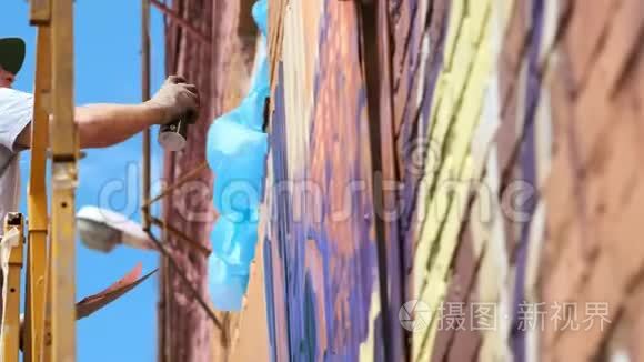 低景：一位年轻的男性艺术家在墙上画一罐涂鸦颜料。 它应该在建筑塔上。 一个男人