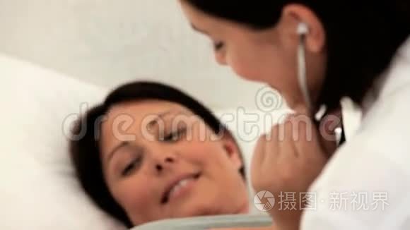 护士倾听她怀孕病人的腹部视频
