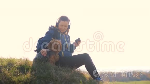 中年妇女和狗约克郡的游客带着背包在耳机里听音乐看着
