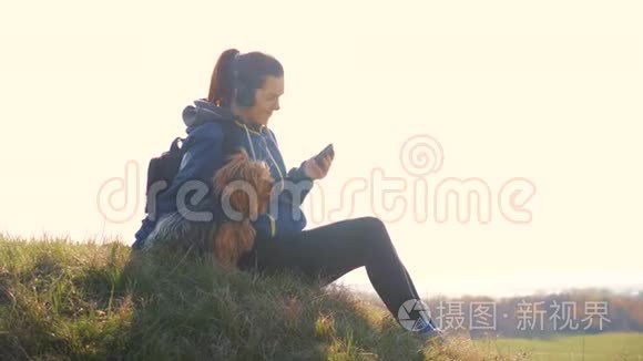 中年妇女和狗约克郡的游客带着背包在耳机里听音乐看着