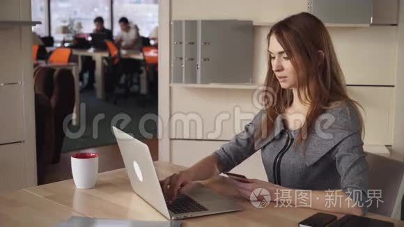 网上银行。 美丽的女人在工作场所用信用卡支付