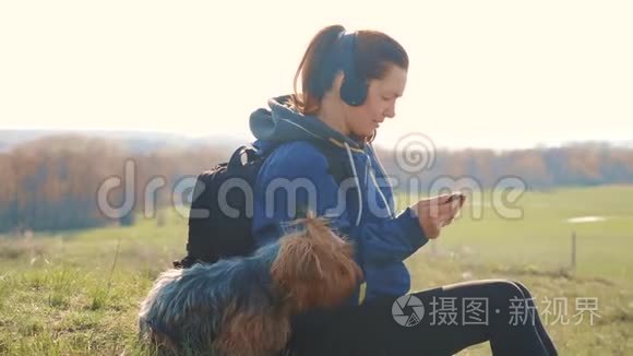 中年妇女和狗约克郡的游客带着背包在耳机里听音乐看着