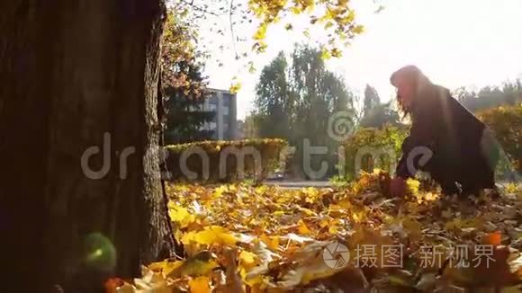 一个女孩从树枝上扔出黄色的叶子