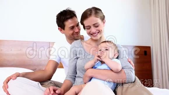 快乐的父母和他们的小儿子坐在床上