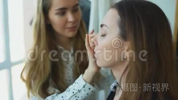 年轻的化妆师在一个重要的活动前为一个女孩做漂亮的化妆面部特写