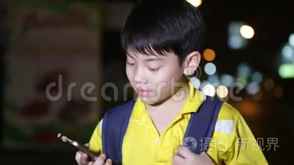 亚洲小孩在夜间灯光背景下玩智能手机